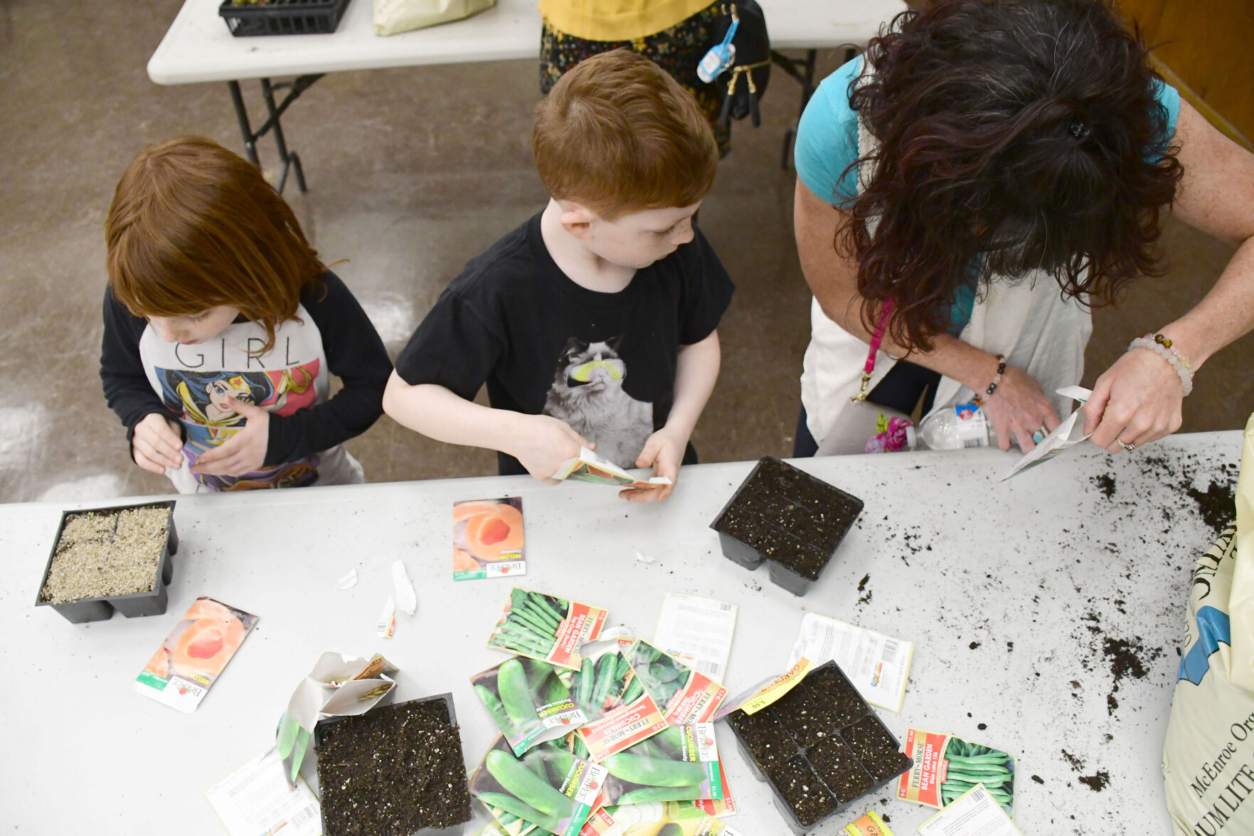A view from above of three people planting seeds